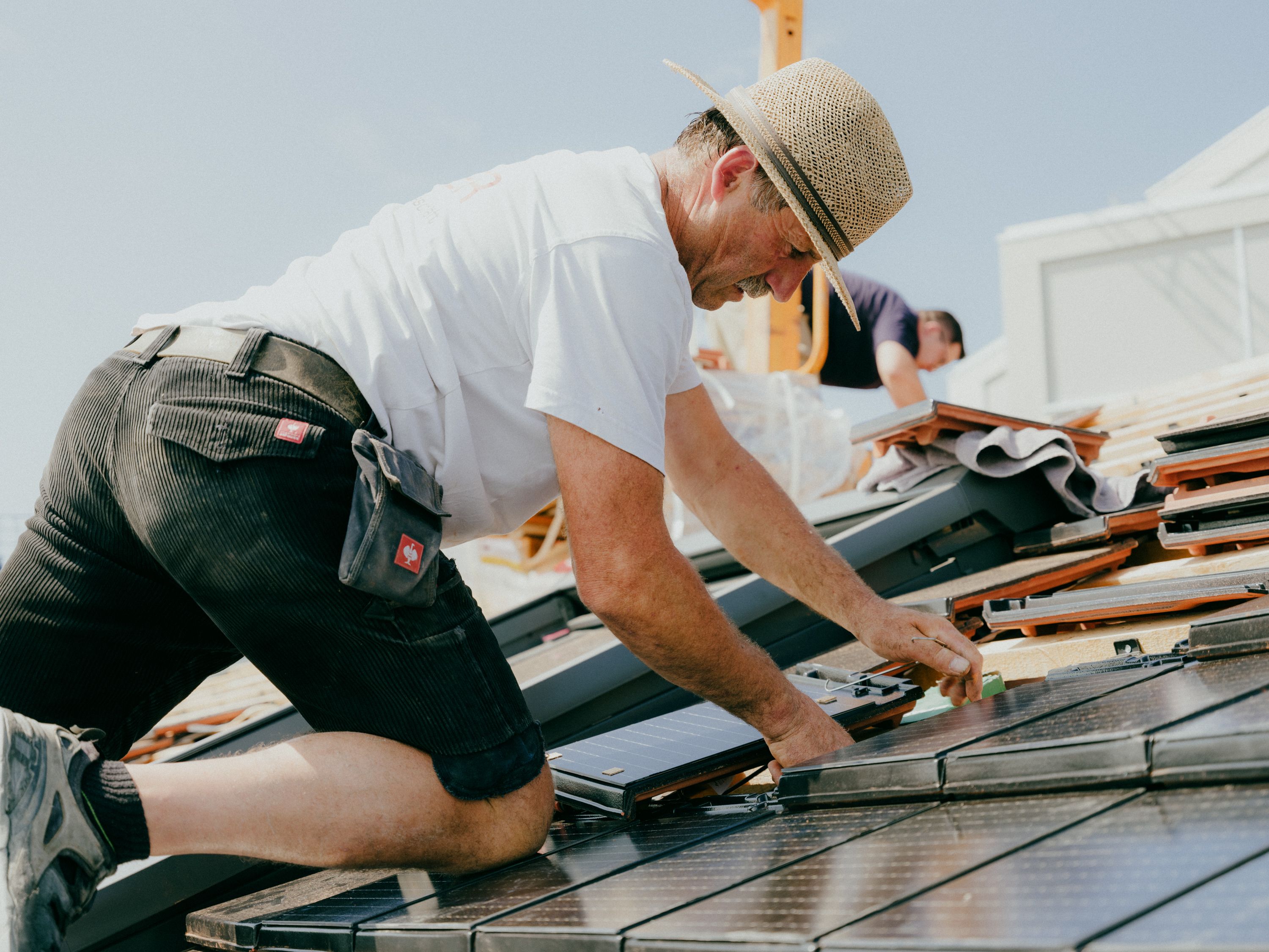 Ein Handwerker auf einem Dach bei der Installation von Solardachziegeln