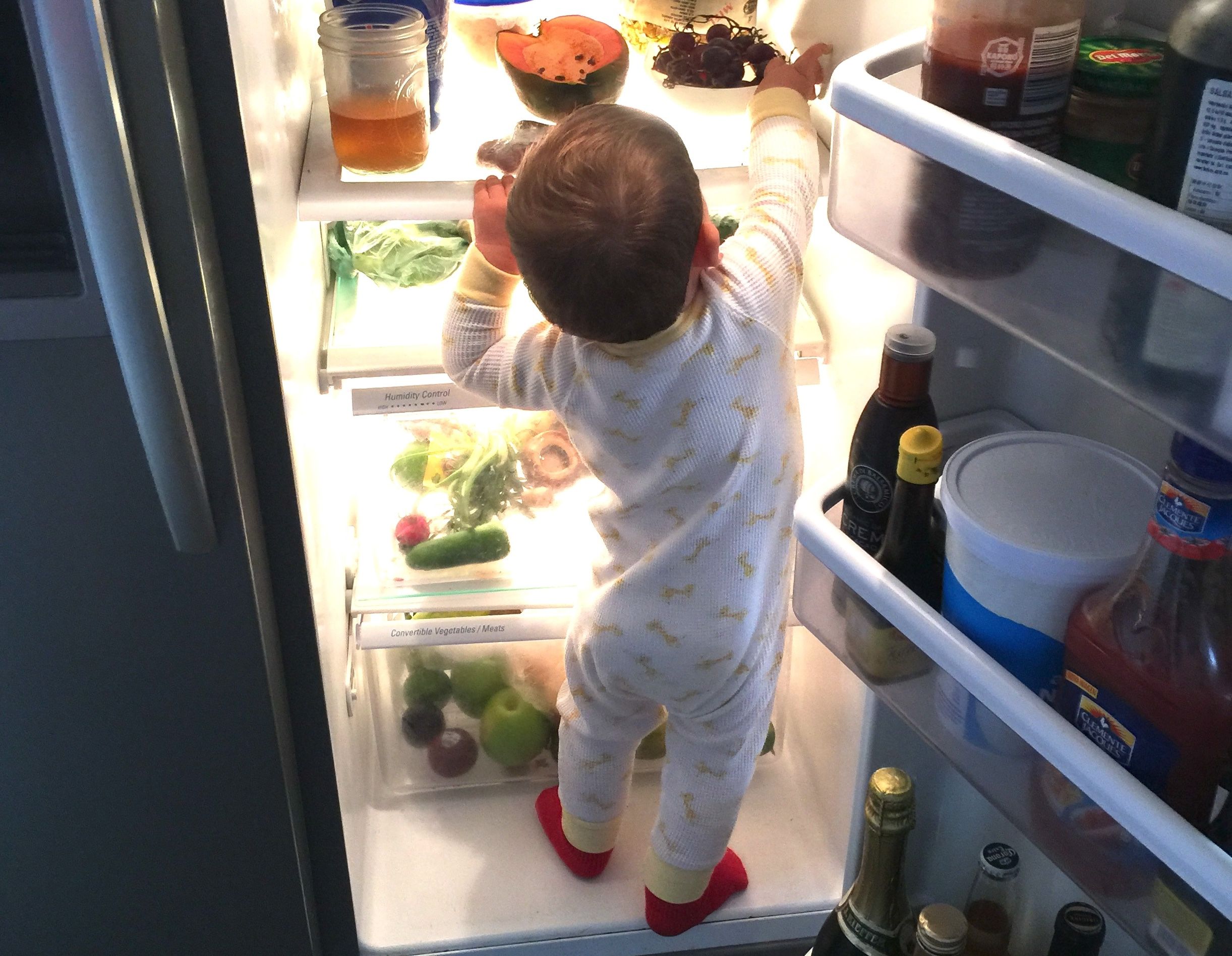 offener Kühlschrank mit Kind davor